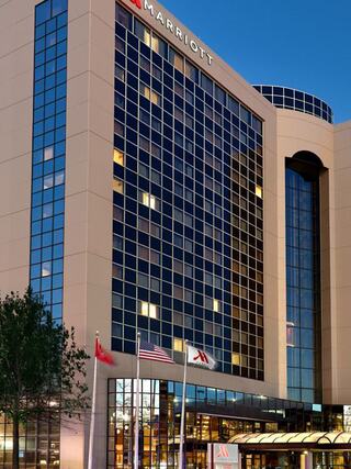 Marriott Chattanooga Downtown hotel exterior at dusk, featuring tall glass windows, a modern entrance canopy, and flags at the front.
