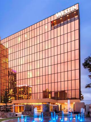Exterior of The Westin Chattanooga at sunset, with reflective glass windows glowing pink and blue-lit fountains in the foreground.