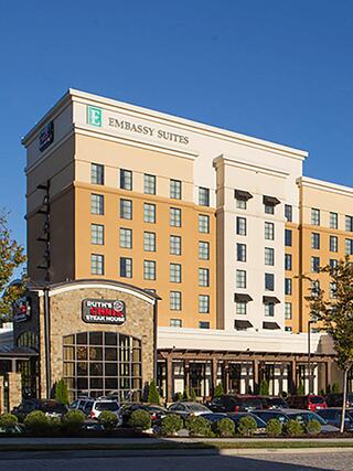 Exterior view of Embassy Suites by Hilton Hamilton Place featuring modern hotel architecture, prominent Embassy Suites signage, and an adjacent Ruth’s Chris Steak House entrance.