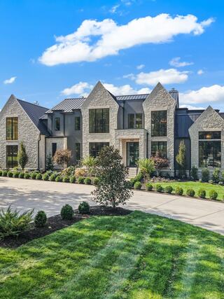 Exterior view of a custom 2K Development home featuring modern architecture, stone façade detailing, expansive windows, and professionally landscaped grounds.