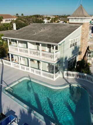 Aerial view of Islander Inn featuring coastal-style architecture, private balconies, and a resort-style pool near the waterfront in a tropical setting.
