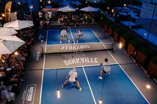 Rooftop pickleball court at Bobby Hotel Nashville – evening match at Rooftop Lounge with city views, crowd seating, and Dinkville-branded court.