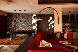 Penthouse Suite at Bobby Hotel Nashville – luxury hotel suite with modern decor, velvet sectional sofa, statement lighting, pool table, and private bar area.