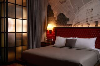 King Guestroom at Bobby Hotel Nashville – stylish hotel room with tufted red leather headboard, modern mural artwork, ambient lighting, and luxury bedding.