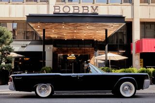 Front entrance of Bobby Hotel Nashville – iconic boutique hotel in downtown Nashville featuring vintage black Lincoln Continental and stylish wood-accented porte-cochère.