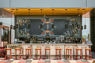 Rooftop Lounge at Bobby Hotel Nashville – stylish outdoor bar with colorful tile flooring, red stools, custom mural, and skyline views in downtown Nashville.